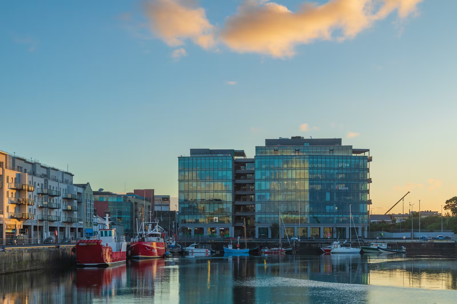 Bonham Quay offices and boats reflected in Galway harbour in evening light